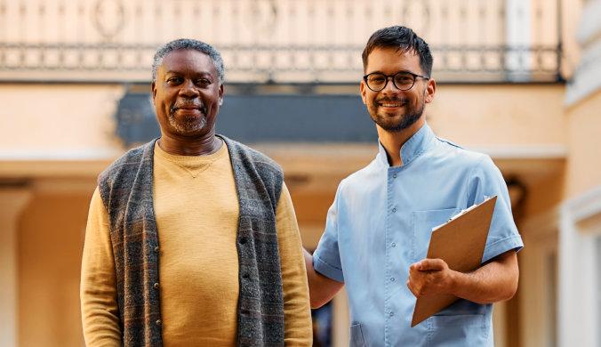 male caregiver with an elderly man smiling