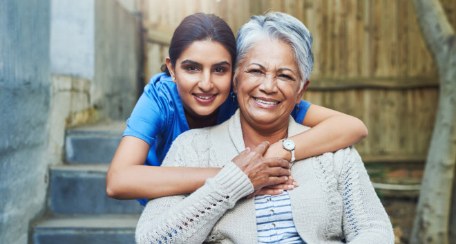 female caregiver hugging an elderly woman smiling